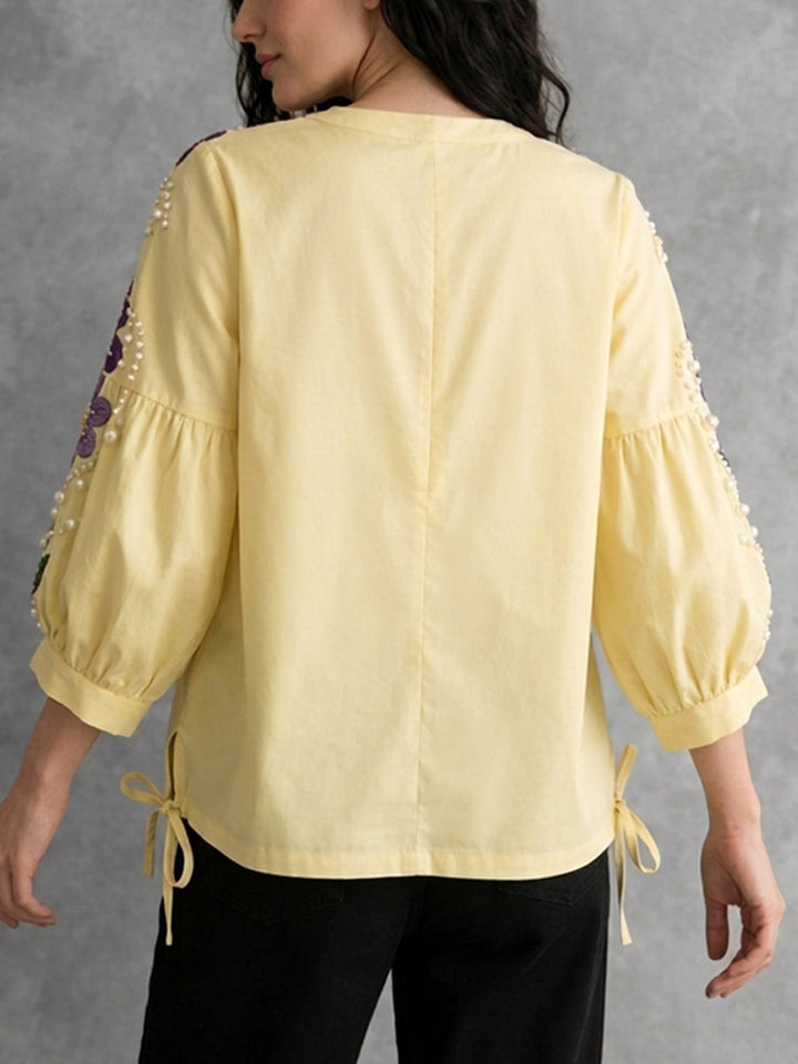 Detailansicht der gelben Damenbluse mit Stickerei, Kontrastdetails und Puffärmeln