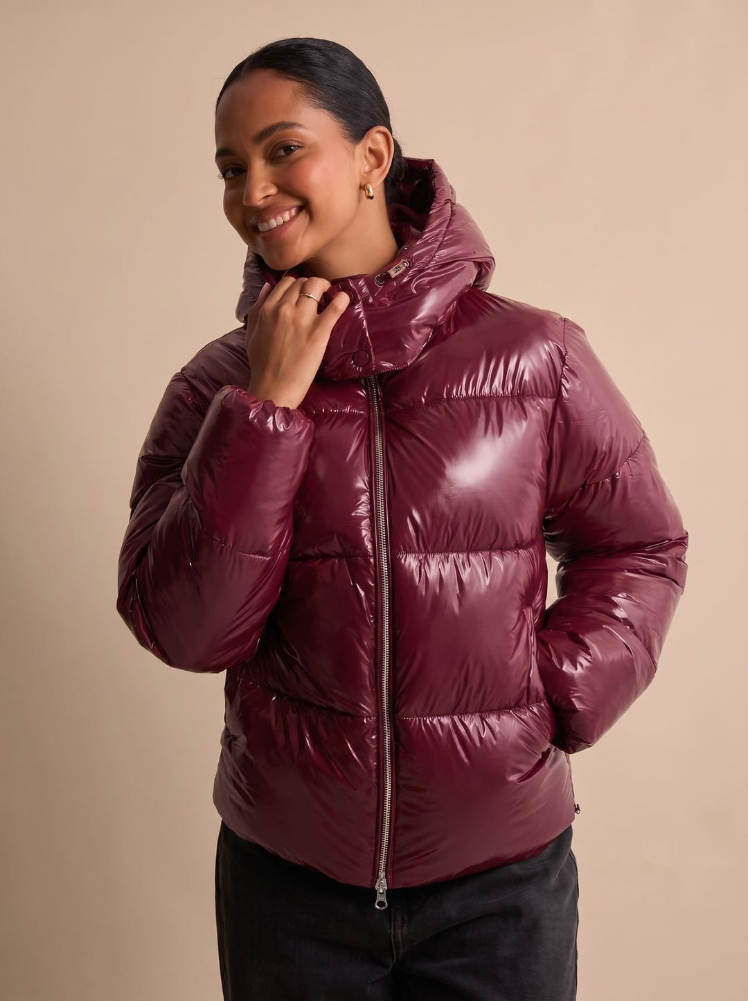 Seitliche Ansicht einer glänzenden Damen-Steppjacke mit Kapuze und Reißverschluss